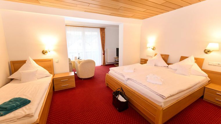 Een gezellig slaapkamer met twee bedden en een eenpersoonsbed. De ruimte heeft een warme, uitnodigende sfeer en veel daglicht.