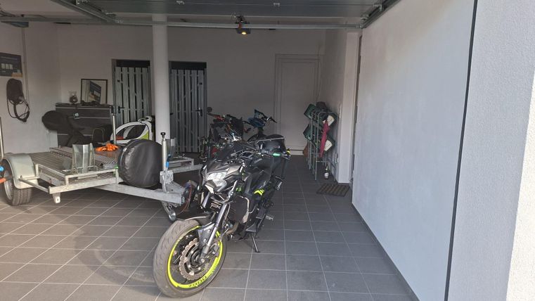 Un dépôt de motos moderne avec une machine noire et des accents jaunes. À l'arrière-plan, d'autres véhicules et bicycles sont visibles.