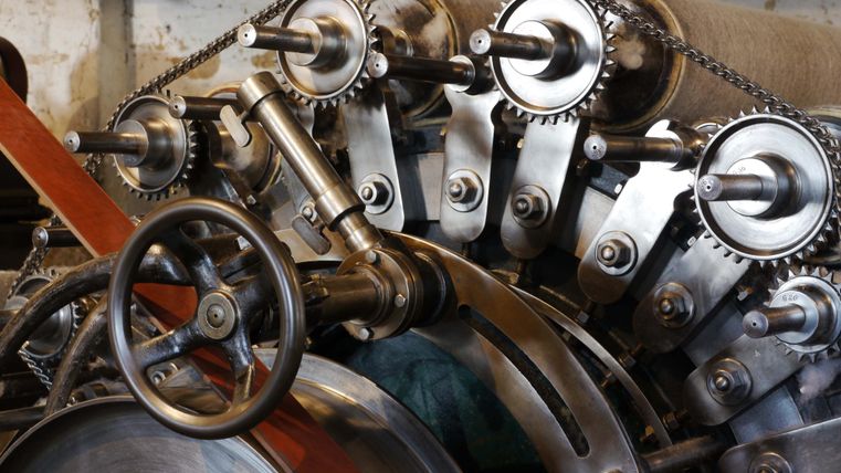 Une vieille installation de machines avec des rouages et une transmission par chaîne. Les pièces métalliques montrent la mécanique dans le domaine industriel.