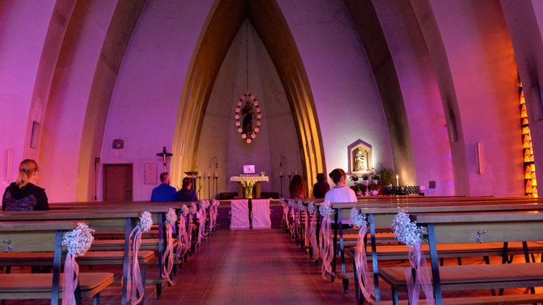 Innenbereich der Schwanenkirche in Roes mit Blick auf den Altar. Durch die bunten Fenster strahlt der Innenraum lila.