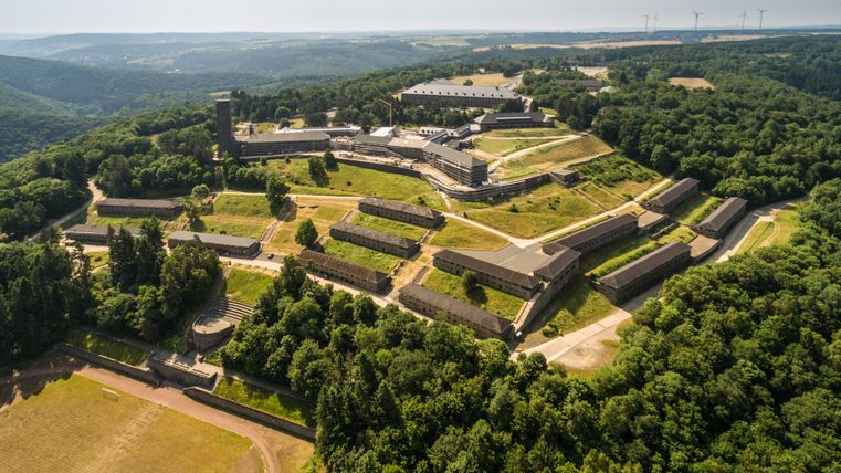 Luchtfoto van Vogelsang IP in de Eifel, omgeven door bossen en heuvels.