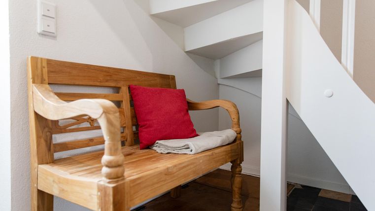 Eine Holzbank steht neben einer Treppe. Auf der Bank liegt ein Handtuch und ein rohes Kissen.