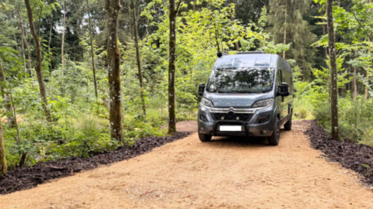 <p>Une caravane sombre arrive sur l'emplacement. L'emplacement est situé au milieu de la forêt</p>
