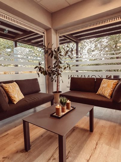 Un espace d'attente confortable avec deux canapés et une table. Une plante et des bougies créent une atmosphère accueillante.