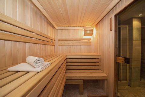 A bright sauna with wooden benches and soft lighting. A fresh towel is ready.