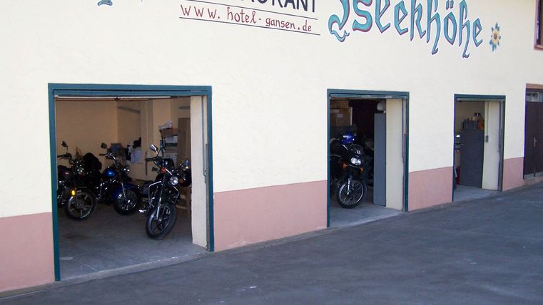 Een garage met meerdere motorfietsen en een restaurant op de achtergrond. De gevel is licht en uitnodigend.