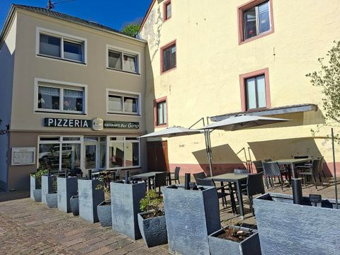 A pizzeria with an outdoor area on a charming street. Tables and chairs are set up under umbrellas.