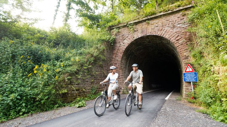 Deux cyclistes sortent d'un tunnel sur la Vennbahn près de Lommersweiler.