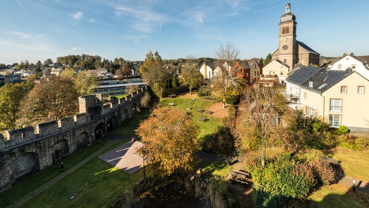 Gezicht op Hillesheim met stadsmuur en kerk op de achtergrond.