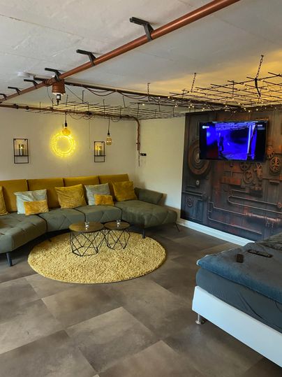 Living-sleeping room with couch and bed, tiled floor, round carpet in front of the sofa.