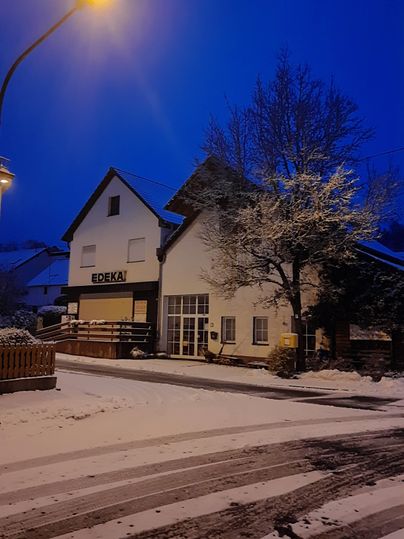 Ein Geschäftshaus im Schnee bei Nacht. Die Umgebung ist ruhig und schneebedeckt.