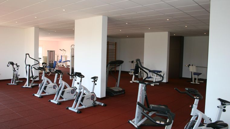 A modern gym with multiple training machines. The room is bright and well-equipped.