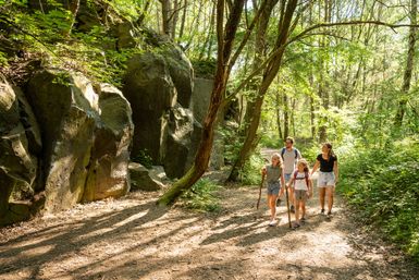 Familie wandert entlang einer Wand aus Vulkangestein