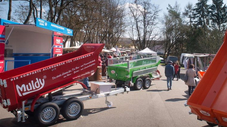 Een straatmarkt met verschillende kleurrijke kraampjes. Mensen slenteren tussen de stalletjes en genieten van de gezellige sfeer.