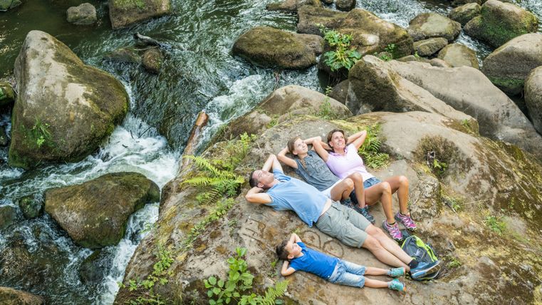 Familie liggend op rotsen bij waterval