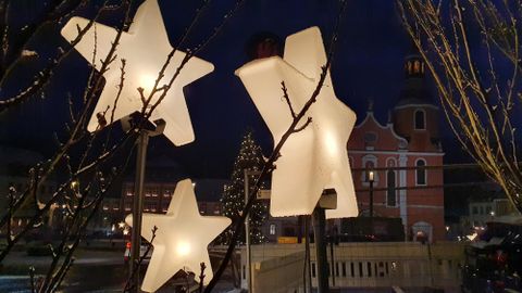 Christmas decoration with shining stars in front of a historic building facade. The scene radiates a festive atmosphere and is surrounded by a dark evening sky.