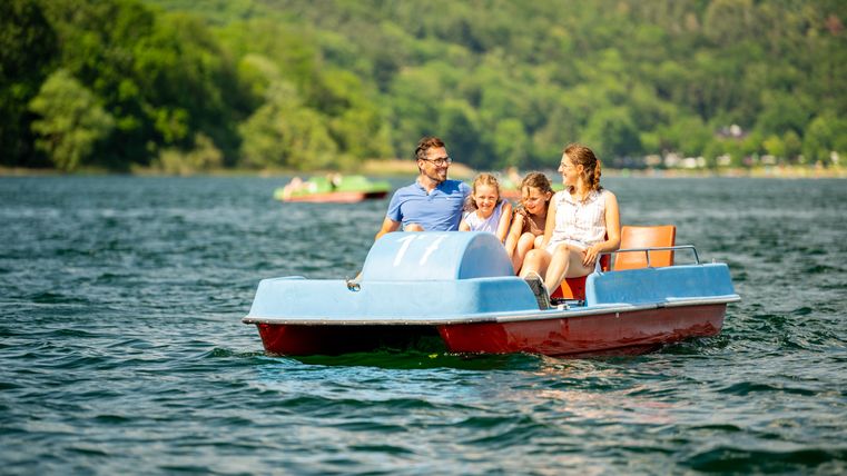 Eine vierköpfige Familie in einem Tretboot auf dem See