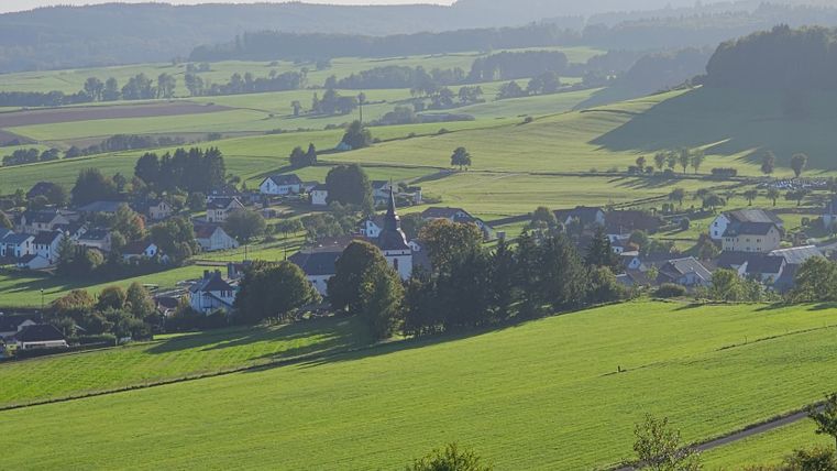 Landscape view of Steffeln with green fields and village in the background.