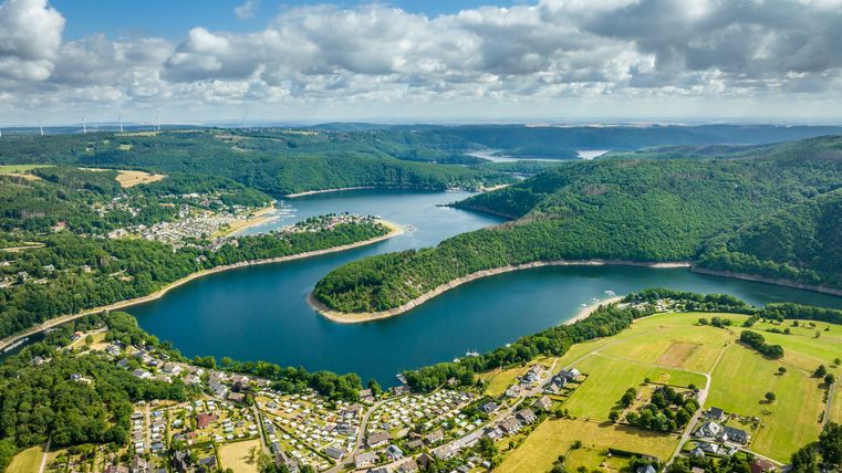 Blick auf einen Stausee der sich schlängelt inmitten von Wald