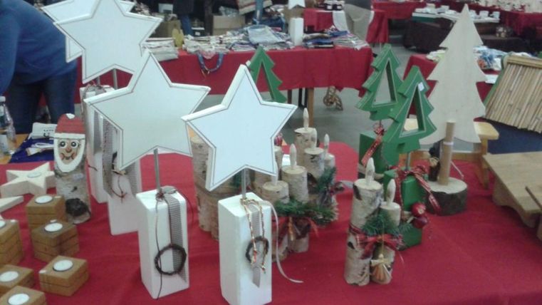 Une surface de vente avec des décorations de Noël faites à la main. On y voit des étoiles, des sapins et différentes petites figurines sur une table rouge.