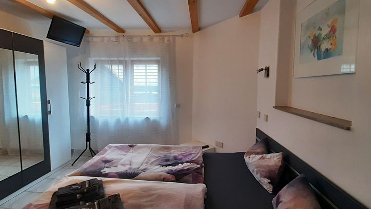 Une chambre confortable avec deux lits et un grand mur de miroirs. La pièce a des murs clairs et beaucoup de lumière naturelle.