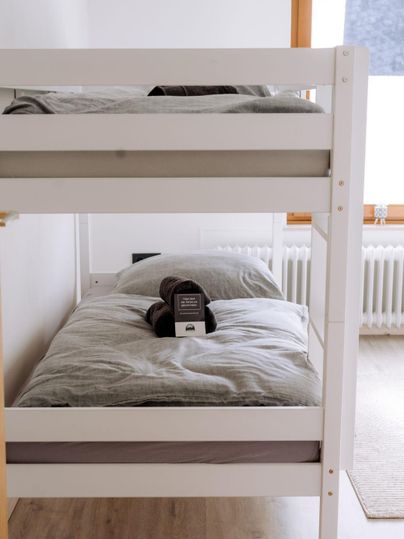A simple bedroom with a bunk bed. The beds are decorated with gray bedding and a pillow.