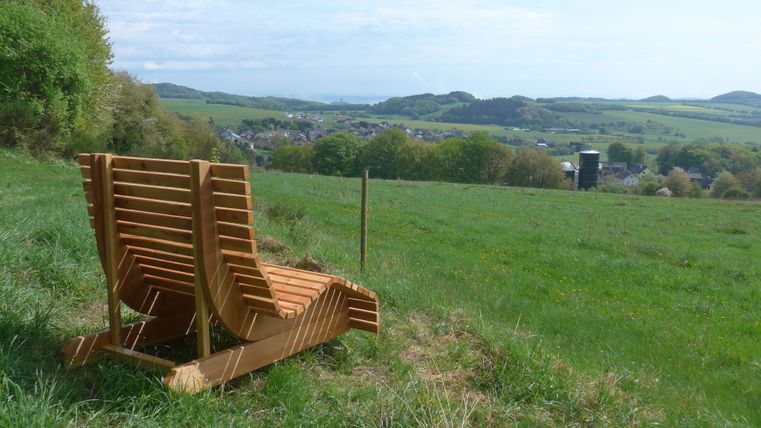 Une tour d'observation en pierre se dresse entre de grands arbres. Le ciel est clair et bleu, et les environs semblent calmes et préservés.