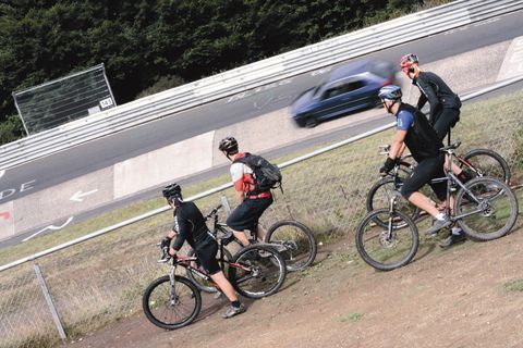 Quatre vététistes observent une voiture sur une piste de course.