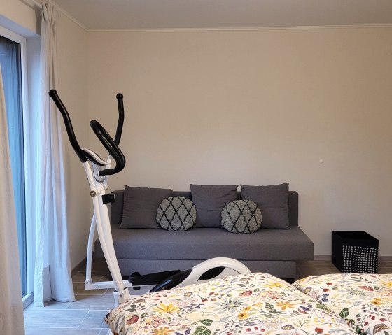 Schlafzimmer mit Hometrainer und Sofa
