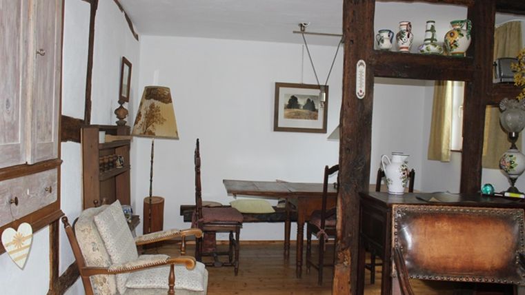 Een traditionele kamer met houten decor en antieke meubels. In de kamer staan een tafel, stoelen en decoratieve voorwerpen.