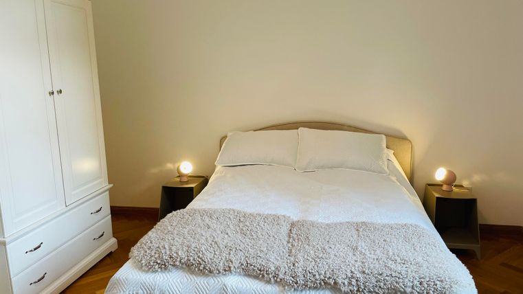 Une chambre confortable avec un grand lit et une housse de couette lumineuse. À côté du lit, il y a deux tables de nuit avec une lampe.