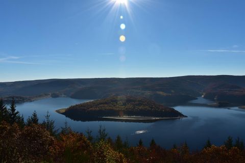 Un paysage pittoresque avec un lac clair et une petite île. Les rayons du soleil se reflètent sur l'eau et entourés de feuillage automnal coloré.