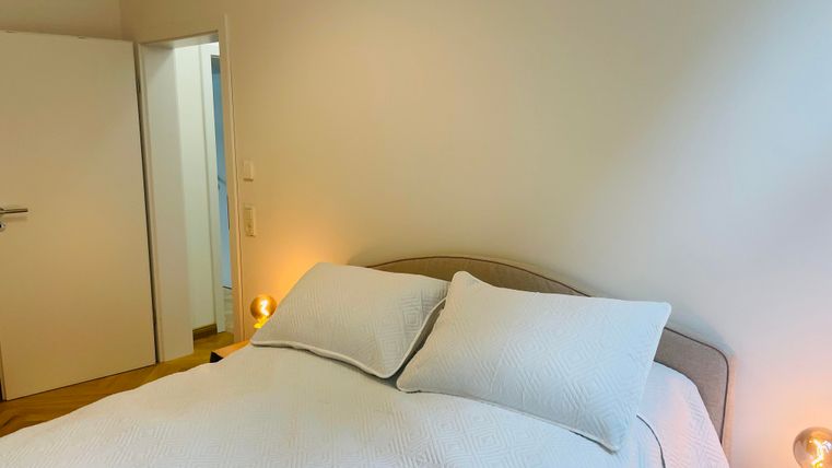 Une chambre confortable avec un grand lit et des coussins doux. Il y a un éclairage doux et une porte qui mène à une salle de bains.