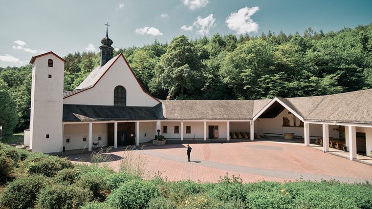 Eine weiß gestrichene Kirche die am Waldrand liegt. 