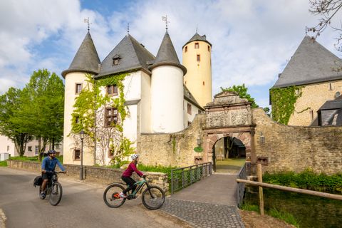 Zwei Radfahrer fahren an der Burg Rittersdorf vorbei.