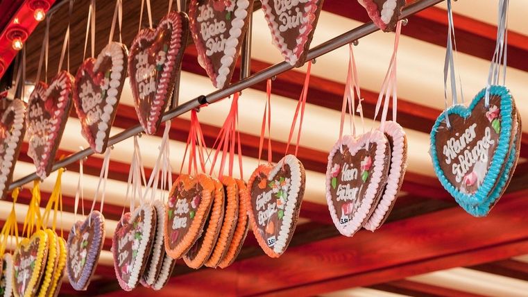 Des fanions colorés pendent entre les arbres sous un ciel clair. La décoration crée une ambiance festive en plein air.