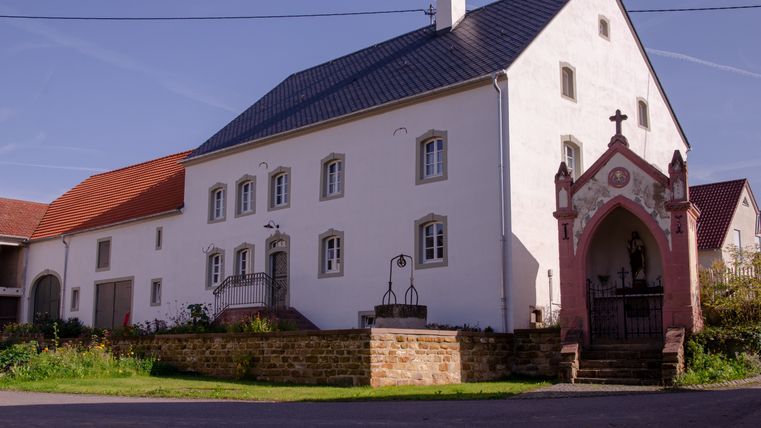 Een oude boerderij met een kleine kapel ernaast.