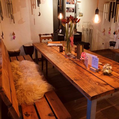 Ein rustikaler Holztisch mit hölzernen Bänken und einem weichen Teppich. Auf dem Tisch stehen Blumen und kleine Dekorationsgegenstände.