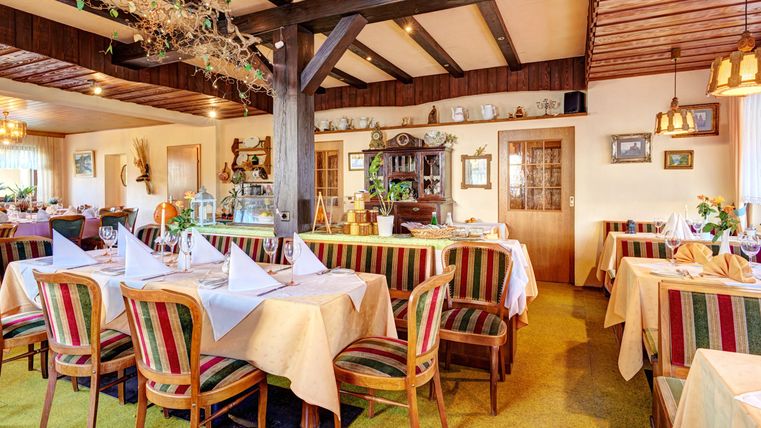 Ein gemütliches Restaurant mit bunten Tischdecken und eleganten Dekorationen. Die Atmosphäre ist warm und einladend, ideal für ein geselliges Essen.