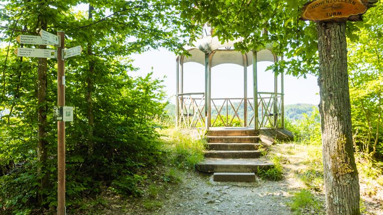 Ein Pavillon im Wald mit einem Wegweiser und einem Schild, das "Hohenzollernturm" anzeigt.