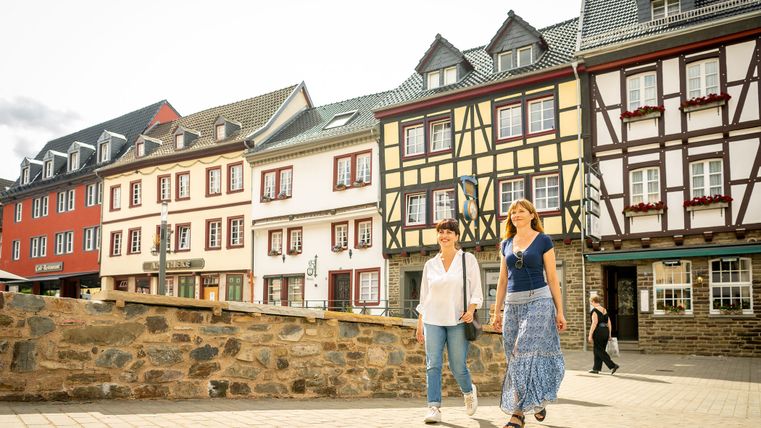Two women walk in front of half-timbered houses in Bad Münstereifel.