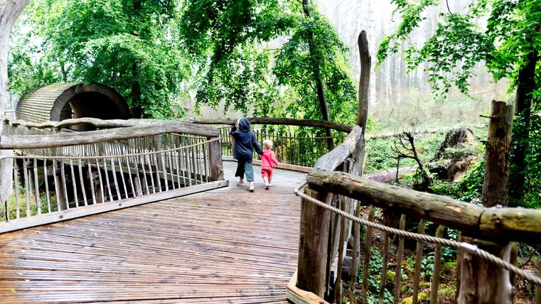 Zwei Kinder auf einem Holzsteg vor einem Holztunnel