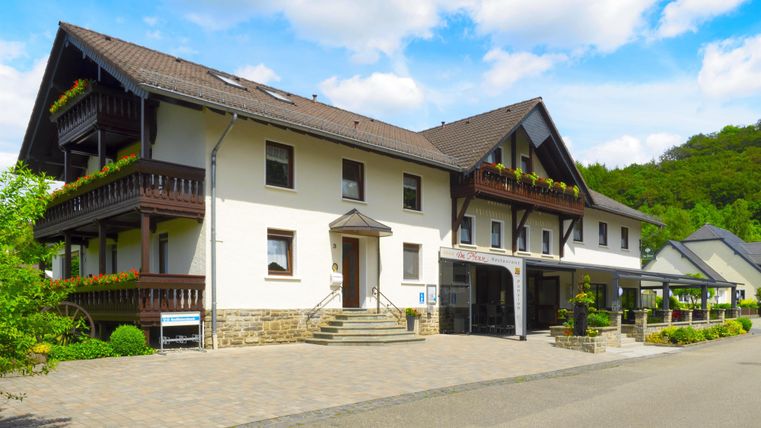 A charming building with multiple floors and balconies. The surroundings are green and invite relaxation.