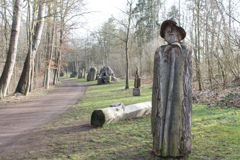 Quelques sculptures au bord du chemin. Devant, une sculpture d'un homme 