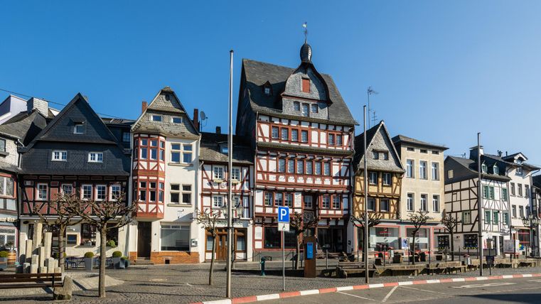 Eine malerische Straße mit historischen Fachwerkhäusern. Der Himmel ist klar und blau, was die charmante Atmosphäre der Stadt unterstreicht.