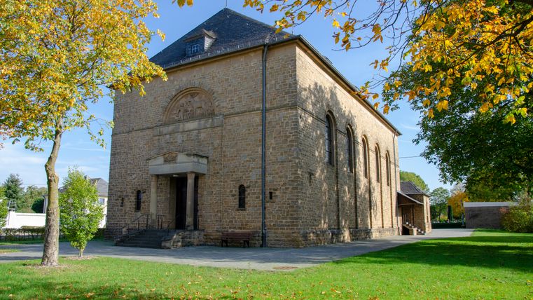 Église Saint-Hubert à Wolsfeld, entourée d'arbres en automne.