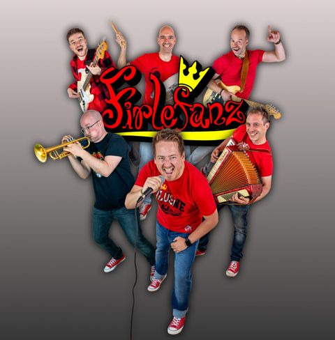 A group of six musicians stands together and plays various instruments. They are wearing red T-shirts and look happy and energetic.