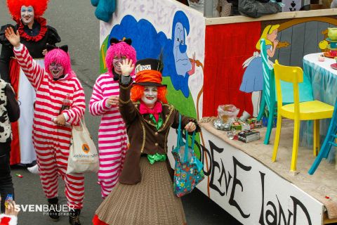 A colorful carnival parade with cheerful clowns in eye-catching costumes. The clowns are smiling and waving at the camera.