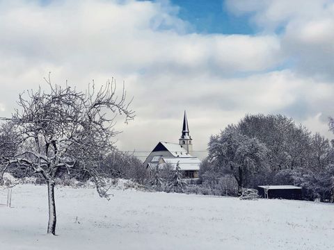 Paysage enneigé avec une église et des arbres en arrière-plan.