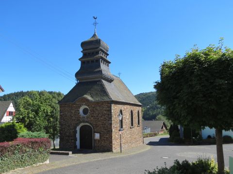 A small, charming church with a characteristic tower.
Surrounded by green grass and beautiful trees in a peaceful landscape.